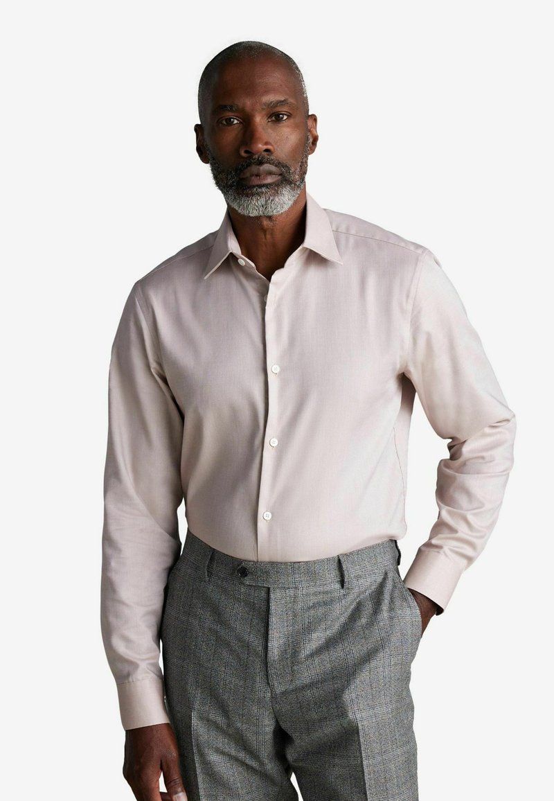 Lichtroze longsleeve shirt met een puntige kraag en knoopsluiting, gecombineerd met grijs checkpatroon broek. Glad materiaal en op maat gemaakte pasvorm.