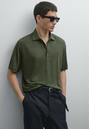 Olijfgroen polo shirt met een knoopsluiting op de kraag, gecombineerd met donkere streepjesbroeken. Draag het met rechthoekige zonnebril en korte mouwen.