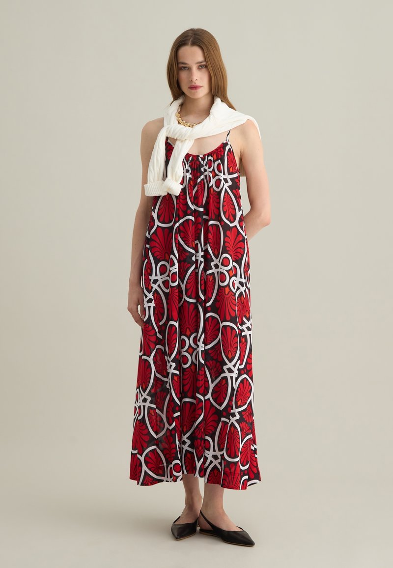 Maxi-Kleid in Rot mit schwarz-weißer Blumenmuster, leichtes Material, ärmellos mit gerafftem Ausschnitt, kombiniert mit einem weißen Pullover.