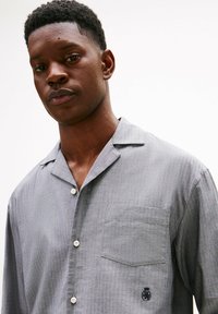 Kurzärmeliges Hemd mit Knopfleiste in Hellgrau, mit einer Tasche auf der linken Seite und dezenter Textur, versehen mit einem kleinen gestickten Logo.