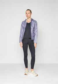 Lightweight lavender jacket with a hood, paired with a black tank top and black leggings, finished with beige sneakers. Smooth texture and fitted design.