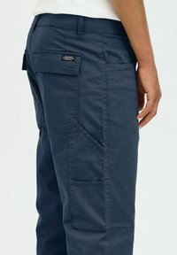 Navy blue cargo pants made of durable fabric, featuring side patch pockets, reinforced stitching, and a waistband with belt loops.