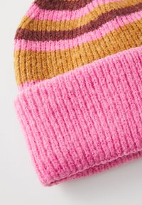Bonnet en tricot avec des rayures horizontales roses, brunes et dorées, doté d'un revers côtelé rose et d'un tissu doux et texturé.