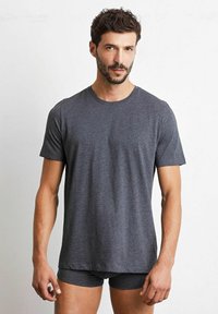 Mörkgrå, kortärmad T-shirt med rund halsringning, gjord av mjuk, strukturerad tyg, bärs med matchande shorts. Enkelt, avslappnat design.