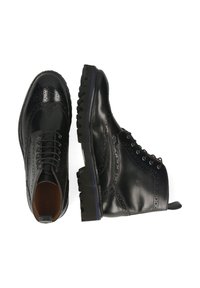Botas de cuero negro con detalles de brogue, suelas texturizadas contrastantes y diseño con cordones. Puntas redondeadas y construcción robusta.