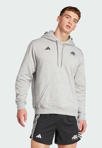 Grå hoodie med framficka, dragsko för huva och svarta detaljer. Matchad med svarta shorts med vita ränder och logotyp.