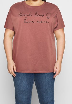 Personne portant un t-shirt rose poudré à manches courtes avec le texte « think less & live more » et un jean bleu, visible des épaules aux hanches.