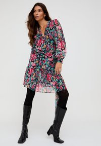 Blumenkleid mit V-Ausschnitt, Puffärmeln und gerüschtem Saum. Hat einen schwarzen Hintergrund mit leuchtend pinken, grünen und blauen Blumen.