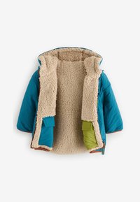 Chaqueta aislante color teal con un forro esponjoso beige, ribete marrón y bolsillos verdes; cuenta con capucha y cierre de cremallera.