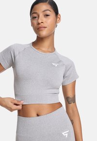 Jasnoszary top w wersji crop, wykonany z elastycznego materiału, z krótkimi rękawami, okrągłym dekoltem oraz białym logo na piersi.