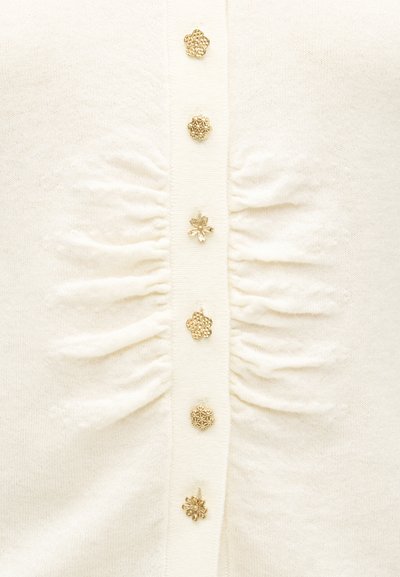 Ivory cardigan with textured fabric, featuring decorative gold buttons and gathered detailing along the front placket.