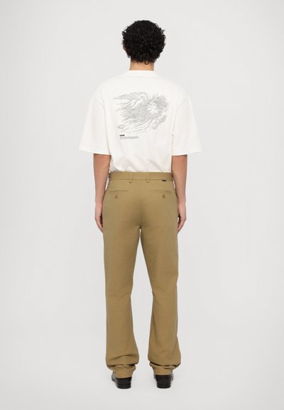 White t-shirt with a graphic print on the back, paired with khaki trousers. The outfit features a relaxed fit and simple design.