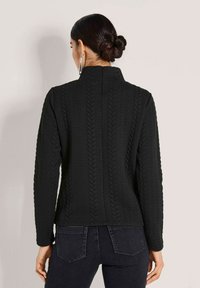 Schwarzer Strickpulli mit hohem Kragen, der ein strukturiertes Kabelmuster, lange Ärmel und eine taillierte Silhouette aufweist. Rückansicht gezeigt.