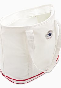 Hvit lerret totebag med glidelås, røde detaljer og doble håndtak; har et rundt Converse All Star-logo på den ene siden.