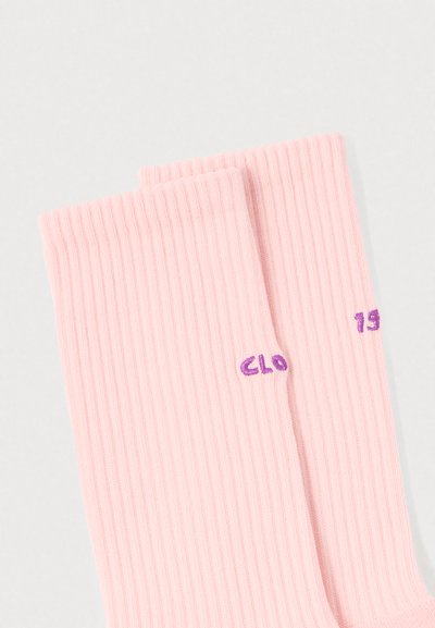Ροζ ριμπ κάλτσες με μωβ κεντημένο κείμενο "CLO" και "75" στις πλευρές. Μαλακή υφή και κλασικός σχεδιασμός μήκους μέχρι τον αστράγαλο.