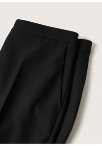 Pantalon noir sur mesure plié avec ceinture apparente et poche latérale sur fond clair.