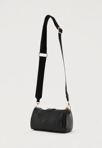 Μαύρη τσάντα ώμου κυλινδρικού σχήματος, κατασκευασμένη από γυαλιστερό δέρμα, με αποσπώμενο ιμάντα και μεταλλικά στοιχεία σε χρυσό χρώμα.