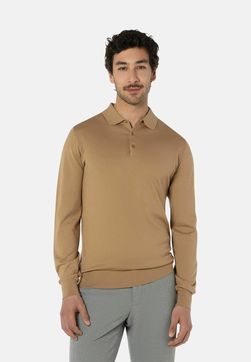 Langärmliges, hellbraunes Poloshirt aus einem weichen Stoff mit Kragen und Knopfleiste mit drei Knöpfen. Kombiniert mit grauen Hosen.