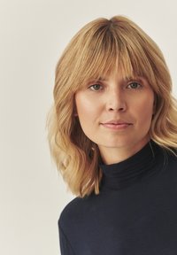 Mornarica majica s visokim ovratnikom i prilagođenim krojem. Meki materijal s glatkom teksturom, koja ima diskretne rebraste detalje oko izreza.