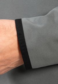 Grå langærmet skjorte med sort manchet. Stofdet ser glat ud og har en subtil tekstur med en ren søm langs armen.