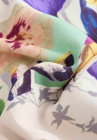 Tessuto floreale con motivi multicolori in tonalità di rosa, viola, verde e blu; texture liscia con un aspetto leggero e fluido.