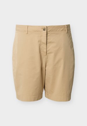 Shorts beige longueur genou avec fermeture à boutons, passants pour ceinture et un design épuré et minimaliste sur un fond uni.
