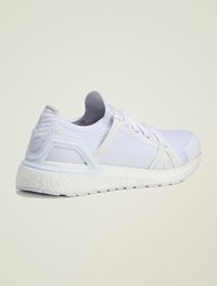 Pantofle sportive albe cu o parte superioară tricotată, detalii texturate și o talpă groasă albă. Prezintă o structură de amortizare vizibilă și închidere cu șireturi.