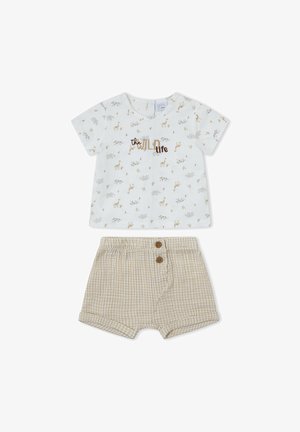 Camisa blanca de manga corta con el texto "the wild life" y pequeños estampados de animales combinada con pantalones cortos de cuadros vichy beige con dos botones marrones.