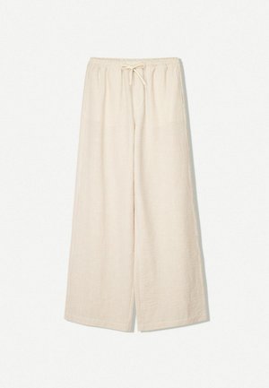 Pantaloni larghi color beige chiaro con vita regolabile, caratterizzati da una sottile texture a righe. Design casual con tasche laterali per maggiore comodità.