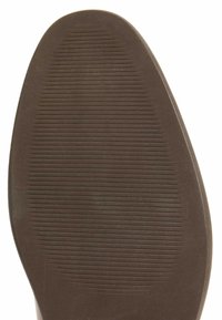 Semelle de chaussure en caoutchouc brun avec des rainures horizontales pour une meilleure adhérence, forme de bout arrondi et surface lisse avec une légère texture.