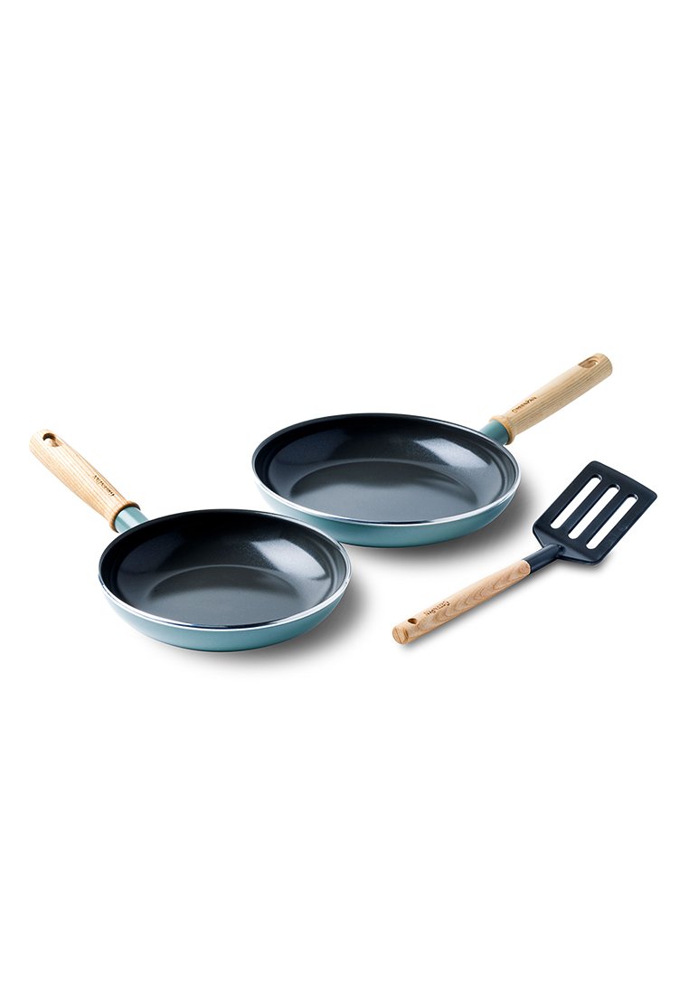 Zwei Bratpfannen mit schwarzem Antihaft-Innenraum und türkisfarbenem Außenbereich, begleitet von einem schwarzen Spatel mit Holzgriff.