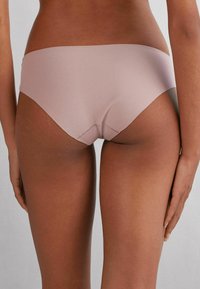 Ljusrosa sömlösa trosor med slät textur, låg midja och formad bakdel för komfort och passform.