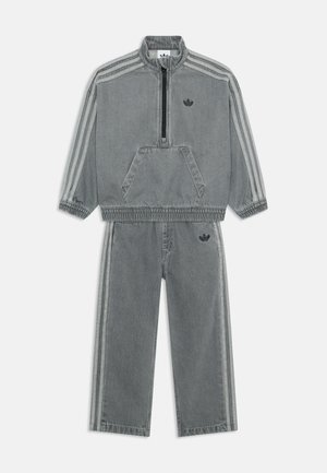 Harmaa denim-harjoitusasu, jossa on neljännesvetoketjullinen collegepaita, jossa on kengurupocket ja joustavat hihansuut, yhdistettynä vastaaviin housuihin, joissa on kontrastivärit.