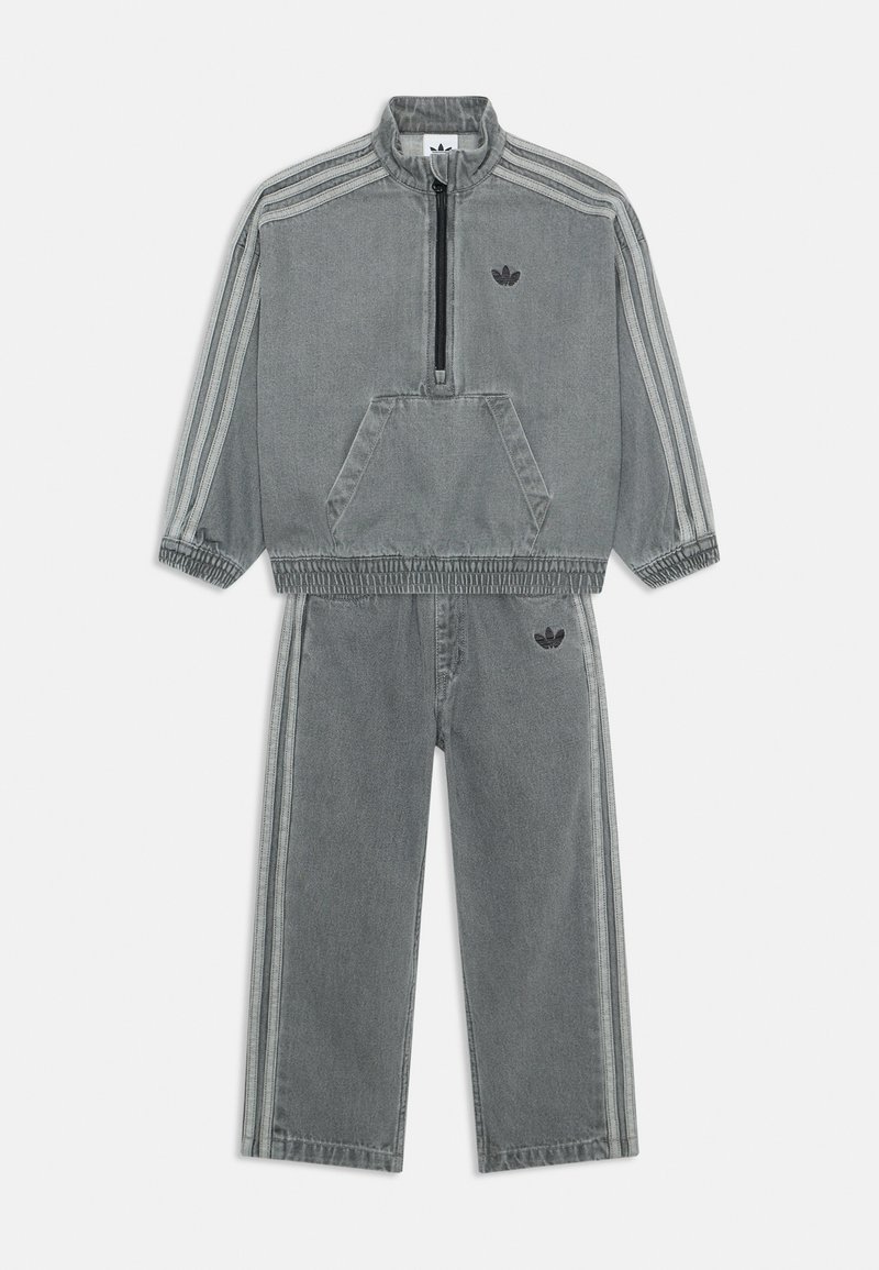 Γκρι τζιν φόρμα που περιλαμβάνει ένα πουλόβερ με τέταρτο φερμουάρ και τσέπη καγκουρό, συνδυασμένο με αντίστοιχες παντελόνες με αντίθετες ρίγες.