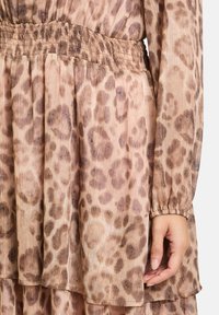 Leopardenmuster-Kleid in Hellbraun und Beigefarben, mit gefaltetem Stoff, einem smockierten Bund und langen Ärmeln mit elastischen Bündchen.