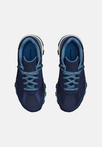 Zapatillas deportivas en color azul marino con materiales de malla y sintéticos. Sus características incluyen cordones de un ligero patrón en azul claro y una suela de goma con un dibujo multidireccional.