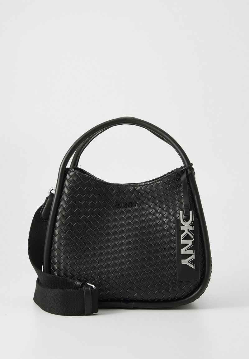 Μαύρη υφαντή δερμάτινη τσάντα με καμπύλο σχήμα, επάνω λαβή και αποσπώμενη καμβάς ζώνη. Διαθέτει μια προεξέχουσα ετικέτα λογότυπου DKNY.