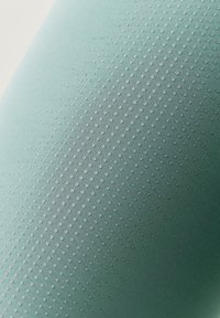 Texturerad tyg i ljusgrön med gradienteffekt, med upphöjda prickar i ett upprepande mönster, slät yta och syntetiskt material.