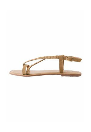 Sandalo piatto tan con design a straptreccia. Presenta un semplice anello per le dita, una cinghia alla caviglia e una chiusura a fibbia. Texture liscia e forma minimalista.