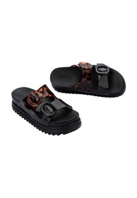 Sandali neri e tartarugati con design a due cinturini, fibbie circolari e suole testurizzate per aderenza. Realizzati in materiale plastico liscio.