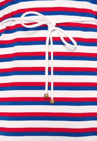 Haut rayé avec des lignes horizontales rouges, bleues et blanches, doté d'un cordon blanc noué et d'accents en perles dorées aux extrémités.