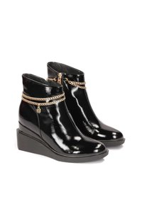 Bottines en cuir verni noir avec un talon compensé, ornées de chaînes dorées et d'une fermeture éclair sur le côté. Texture lisse et design moderne.
