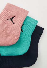 Tri para nogavic: roza, teal in mornarsko modra. Vsaka ima rebrasto teksturo in črn Jumpman logotip na strani.