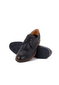 Schwarze Lederschuhe mit abgerundetem Zehenbereich, Schnürdesign und einem braunen Lederakzent an der Sohle. Strukturierte Gummisohle mit kreisförmigen Mustern.