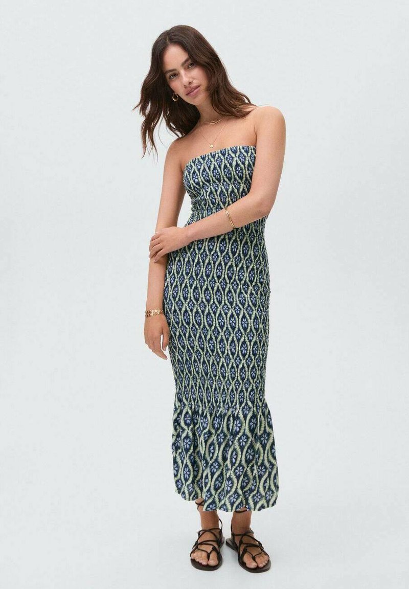 Strapless maxi dress in blue and cream pattern, fitted bodice, flared hem, made from lightweight fabric; worn with black strappy sandals.
