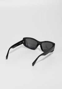 Black sunglasses with a sleek, angular design. Features dark lenses and smooth plastic frames. The arms are elongated and slightly curved.