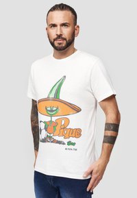 Hvid bomulds T-shirt med en farverig tegneserie-grafik af en karakter med en stor hat og en fodbold, med teksten "Pique" nedenfor.