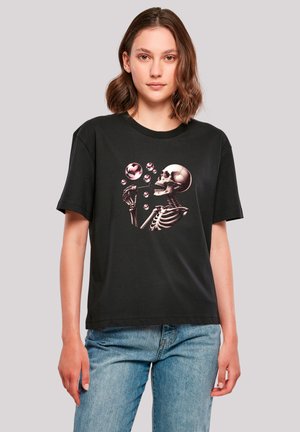 Black cotton t-shirt featuring a skeleton graphic blowing bubbles in pink tones. Short sleeves and a round neckline, relaxed fit.