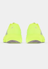 Νεόν κίτρινα αθλητικά παπούτσια με υφασμένο επάνω μέρος, σχεδιασμένα με απορροφητική σόλα και διακριτικές γκρι λεπτομέρειες κατά μήκος των πλευρών.