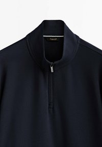Pull bleu marine avec fermeture éclair au quart, col montant et tirette visible, design uni, sans motifs ni logos visibles.